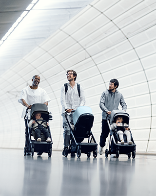 Three fathers walk through a subway with a compact Thule Shine city stroller.